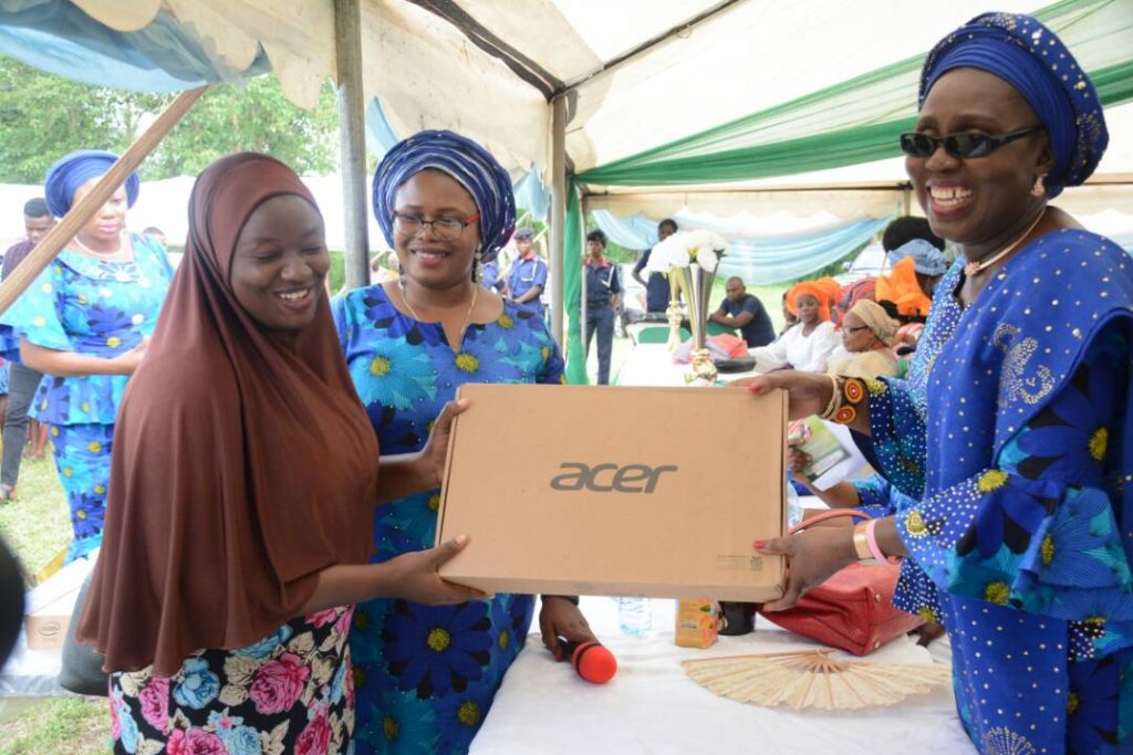 Wife of Ondo State Governor, Arabinrin Betty Anyanwu-Akeredolu (right), presenting hybrid Laptops to one of the beneficiaries (left), during the 6th Forum for Wives of Ondo State Officials, (FOWOSO) Empowerment Outreach Programme for Women, Youths and Special needs people in Akure North Local Government Area of Ondo State. 21st, June, 2018. 